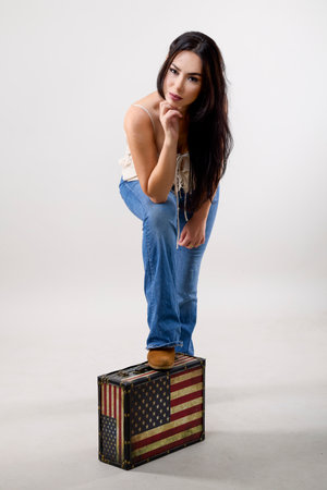 portrait of a beautiful woman posing with a suitcase on gray background, travel concept.の写真素材