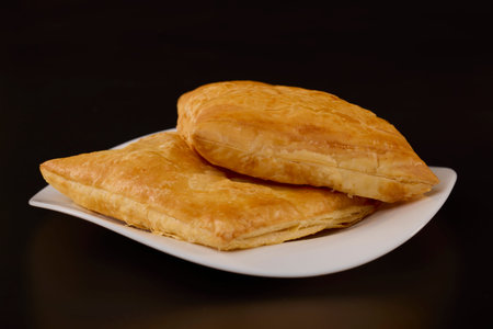 cheese pie on a white plate on a black background.