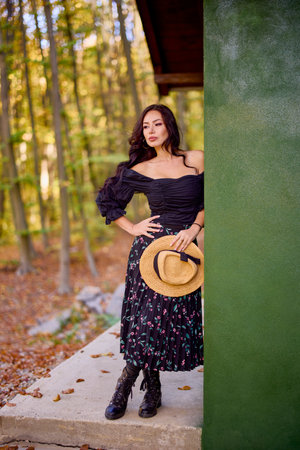 a beautiful woman with a hat near a cottage in autumnの写真素材
