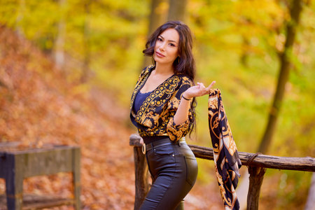 a beautiful woman with a scarf in her hand is enjoying the autumn landscapeの写真素材