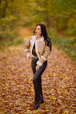 portrait of a beautiful woman with a jacket and pants full body on a road in the autumn forest.の写真素材