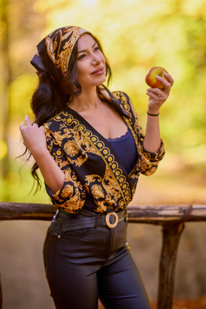 a beautiful woman with a headscarf and an apple in her hand autumn background.の写真素材