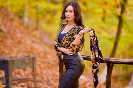 a beautiful woman with a scarf in her hand is enjoying the autumn landscapeの写真素材