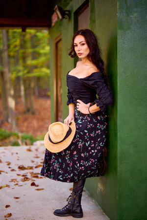 a beautiful woman with a hat near a cottage in autumnの写真素材