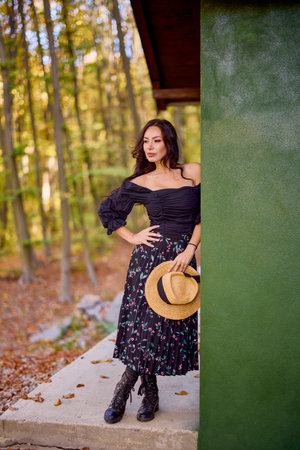 a beautiful woman with a hat near a cottage in autumnの写真素材