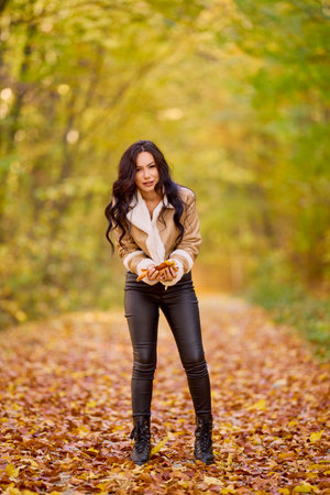 portrait of a beautiful woman with a jacket and pants full body on a road in the autumn forest.の写真素材