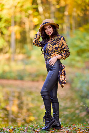 a woman sits on a log near a lake during autumnの写真素材