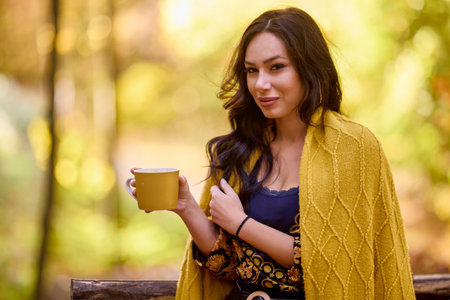 the beautiful brunette a blanket and a book in the forest during autumnの写真素材