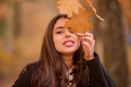 portrait of a beautiful woman with long hair posing in an autumn landscape in a forestの写真素材
