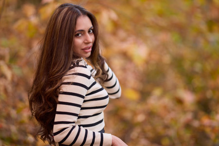 portrait of a beautiful woman with long hair posing in an autumn landscape in a forestの写真素材
