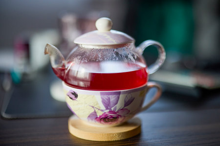 a teapot with tea on a desk with a blurred backgroundの写真素材