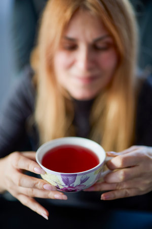 a woman holding a cup of red tea in her handsの写真素材