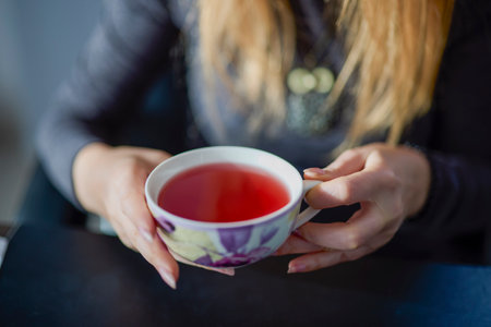 a woman holding a cup of red tea in her handsの写真素材