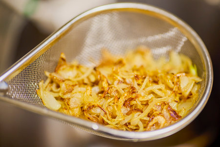a sieve with fried onions that are drainingの写真素材
