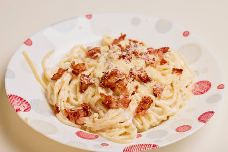 a plate of carbonara pasta on a tableの写真素材