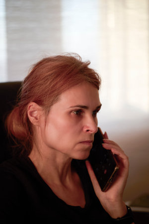 Portrait of businesswoman talking on the phone and having a worried expression.の写真素材