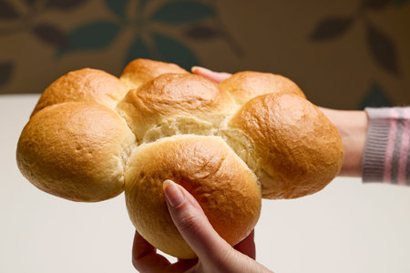 woman's hands breaking a white loaf of bread