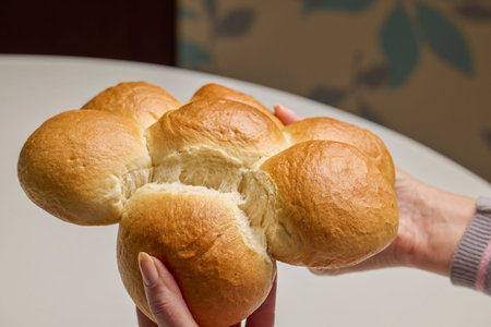 woman's hands breaking a white loaf of bread