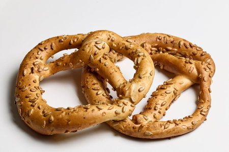 two pretzels with sunflower seeds on a white table