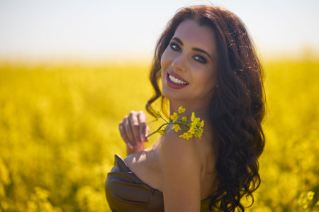 beautiful woman posing in a field of blooming rapeseed