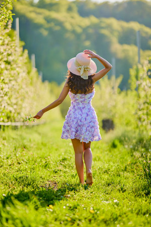 full body portrait of a beautiful woman in a dress in a blooming apple orchard with a blurred backgroundの写真素材