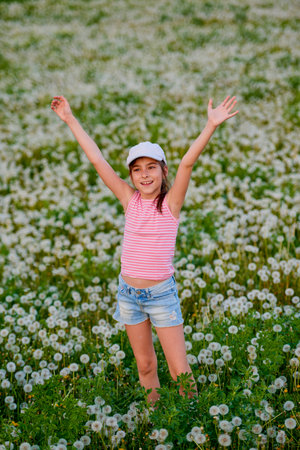 a little girl playing in a dandelion meadow on a spring dayの写真素材