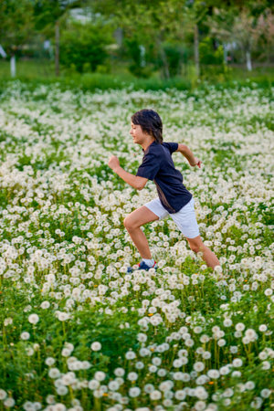 a cute boy playing in a dandelion meadow on a spring dayの写真素材
