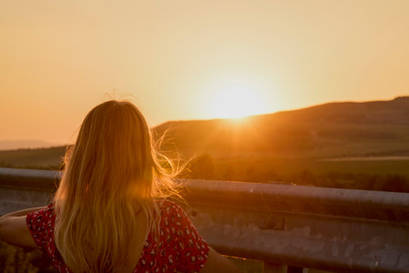 portrait of a woman seen from behind looking at the sunsetの写真素材
