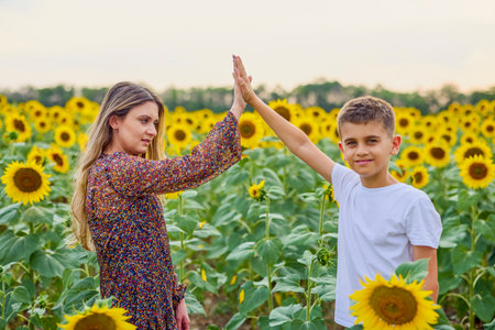 A mother and her son on a farm enjoy a sunflower field on a summer day.の写真素材