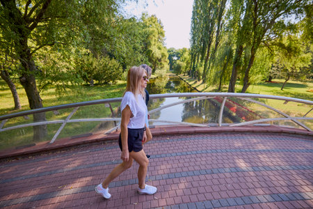 Two middle-aged sisters spending a summer morning in the park by a lake relaxing and having fun.の写真素材