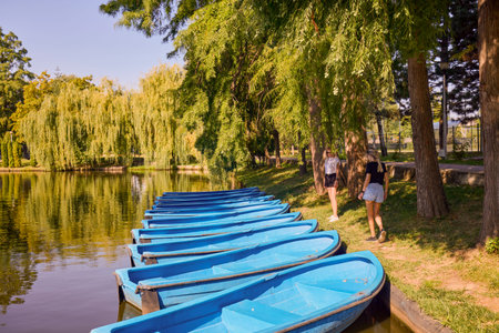 Two middle-aged sisters spending a summer morning in the park by a lake relaxing and having fun.