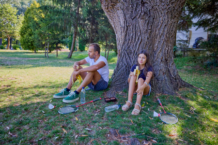 Father and daughter spending time together in the park exercising and relaxing.