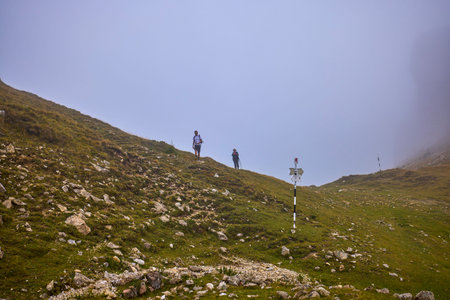 A middle-aged couple hiking up a mountain on a cloudy and foggy day.