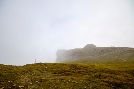 landscape with a rocky mountain ridge in fog during rain