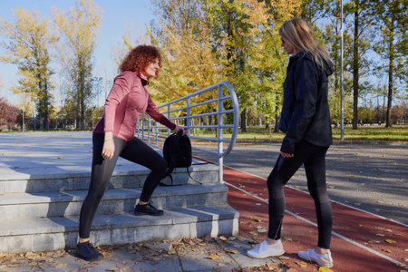 A middle-aged woman in the park with her friend doing sports together on a beautiful autumn day