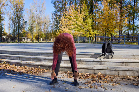 A middle-aged woman in the park is doing warm-up exercises before exercising.