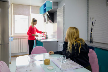middle-aged woman at home in the kitchen with a friend talking over coffeeの写真素材