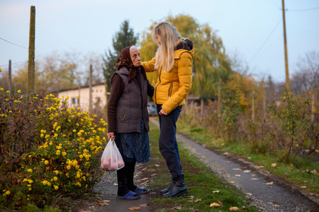 Middle-aged woman visits her elderly mother and walks through the gardenの写真素材