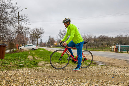 A middle-aged man takes his bike for a ride in the morning.