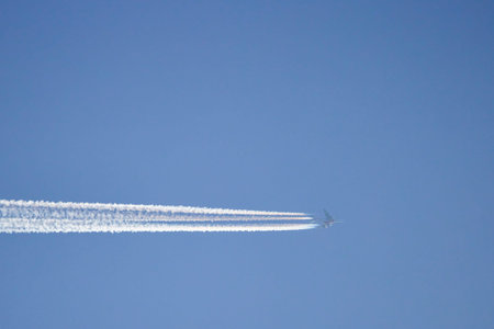 Landscape with a passenger plane leaving tracks behind it in the clear blue sky