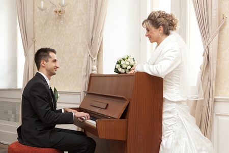 Groom playing piano  Happy bride  の写真素材