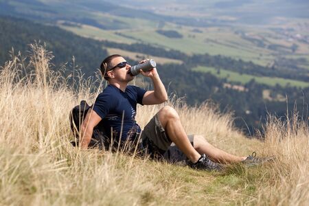 sportive man on the mountain trek, man sit and restの写真素材