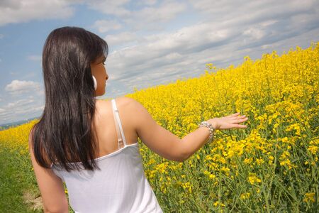 Young woman on yellow rape fieldの写真素材