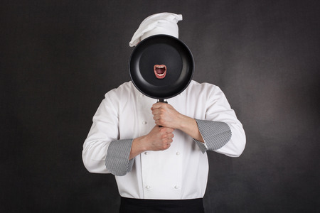 Chef behind pan black background. の写真素材