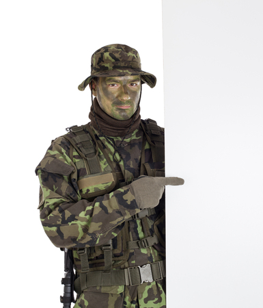 Soldier in camouflage pointing finger to white blank boardの写真素材