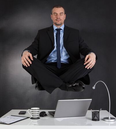 Businessman meditating in the office and in the airの写真素材