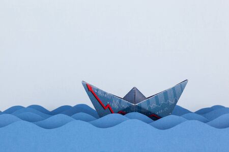 Paper boat made with financial document and swimming on paper waves.の写真素材