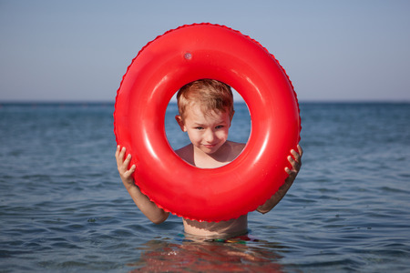 Little boy look out of inflatable ring in the seaの写真素材