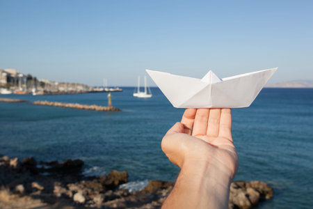 Dream to have a ship. Hand holding a paper boat on the seaの写真素材