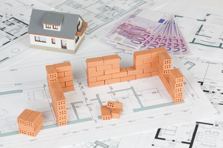 Model house construction with brick on blueprint and five hundred euro banknoteの写真素材